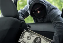 Numismatic Crime – Coin Dealers Homes, Cars Robbed After Shows Stock photo of a thief stealing a $1000 Bill from a car.